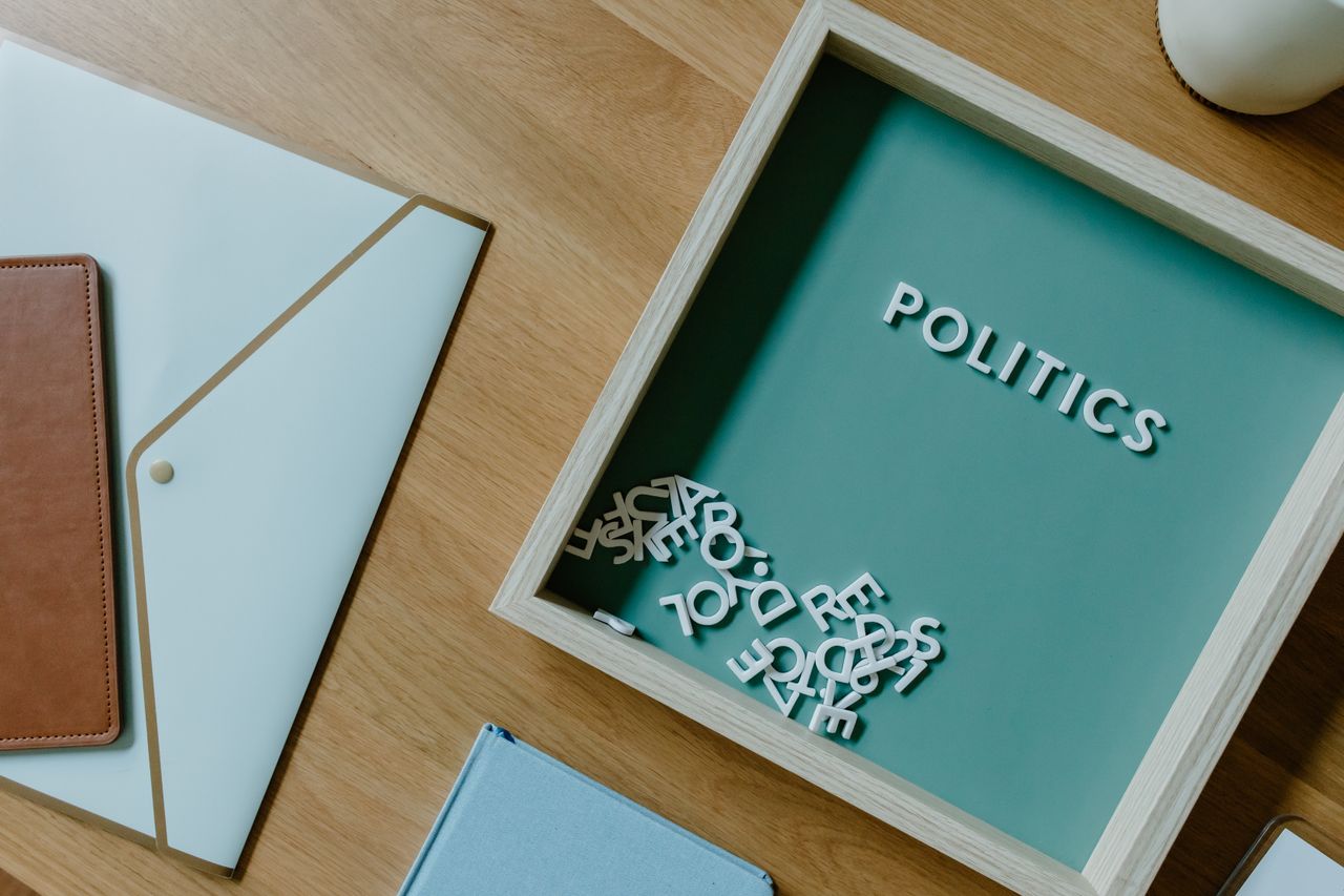 services-04 Top view of a box with POLITICS text alongside office items on a wooden desk.